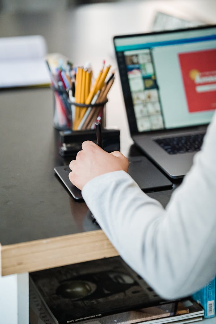 Close-up of a person using a digital tablet and laptop in a modern office setting.